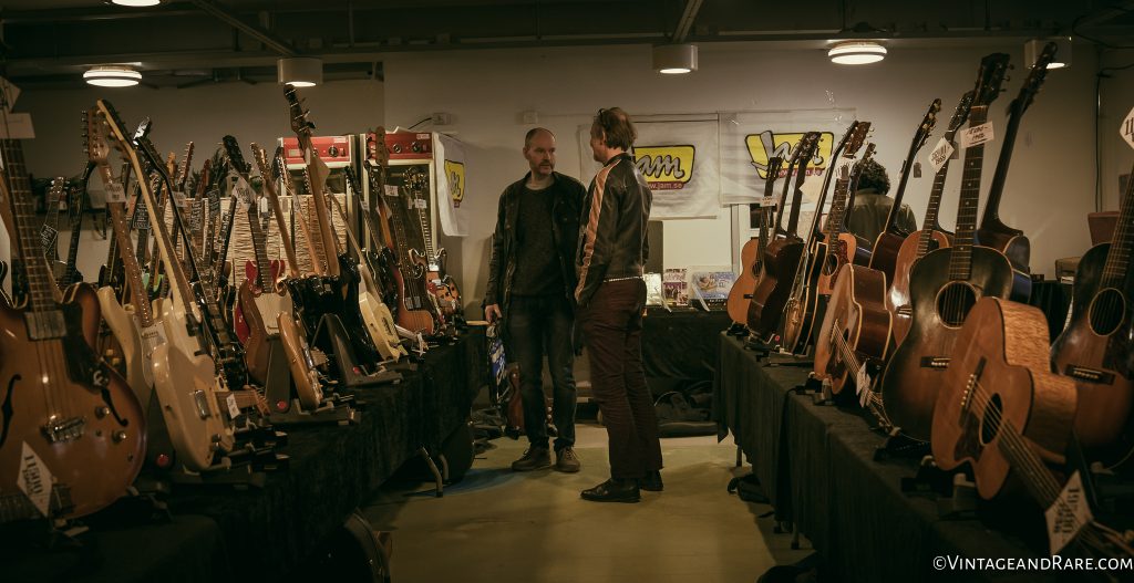 Which one to buy? Gentlemen going over stuff at the booth of V&R seller, Jam Guitars